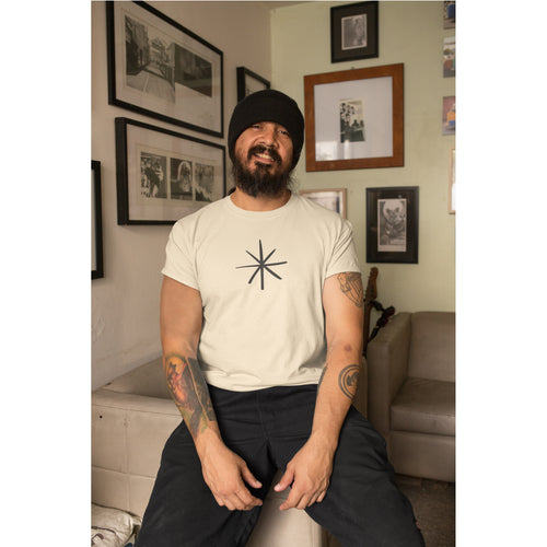 Man sitting in a living room wearing a white t-shirt with a black symbol